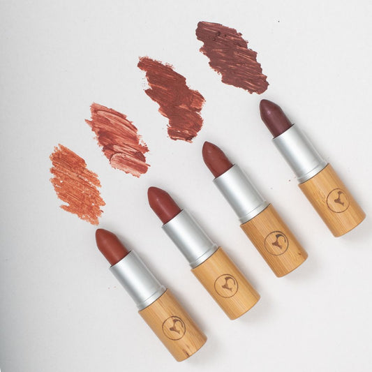 Four lipsticks with wooden accents on a white background