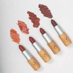 Four lipsticks with wooden accents on a white background